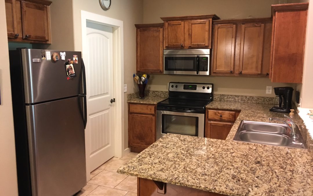 Modern kitchen with stainless steel appliances, granite countertops, wooden cabinets, and a cozy atmosphere, showcasing features relevant to the Lake Willastein Condo listing.