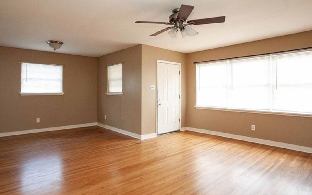 Spacious living room in a newly built duplex, featuring hardwood floors, large windows for natural light, and a ceiling fan, ideal for modern apartment living in West Little Rock.