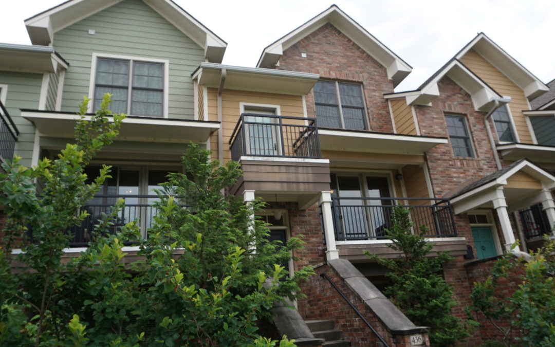 Luxurious Argenta townhome exterior featuring a blend of brick and siding, with a balcony, landscaped greenery, and stairs leading to the entrance, located in the Argenta District of Downtown North Little Rock.