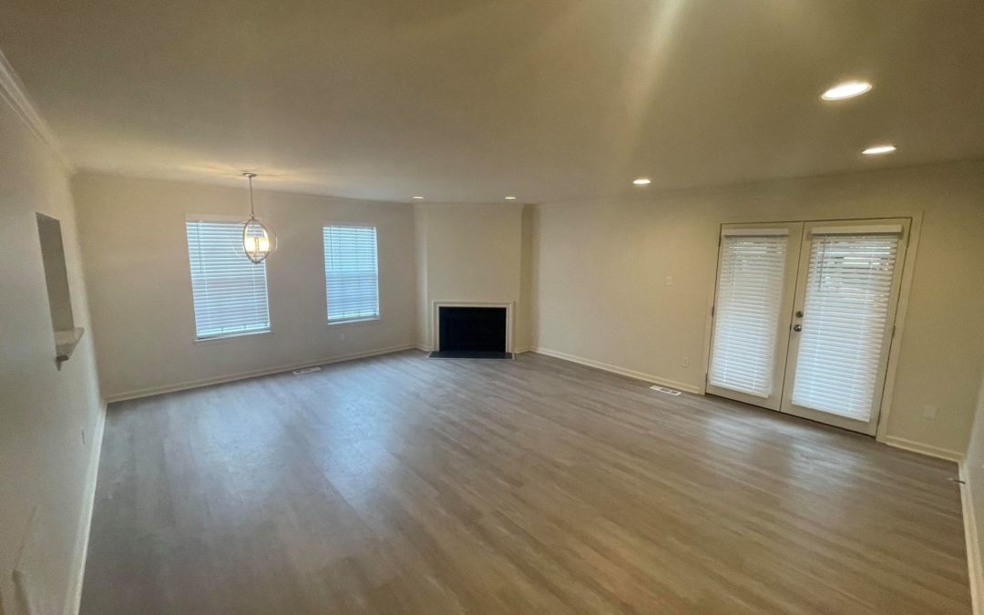 Spacious living room in renovated duplex featuring large windows, modern lighting, and a cozy fireplace, ideal for stylish living in The Heights.