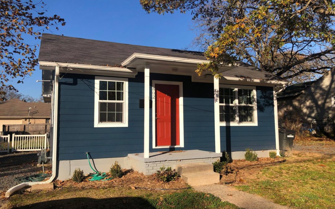 Charming renovated blue apartment exterior with red front door, surrounded by landscaping, located in Little Rock's Argenta District.