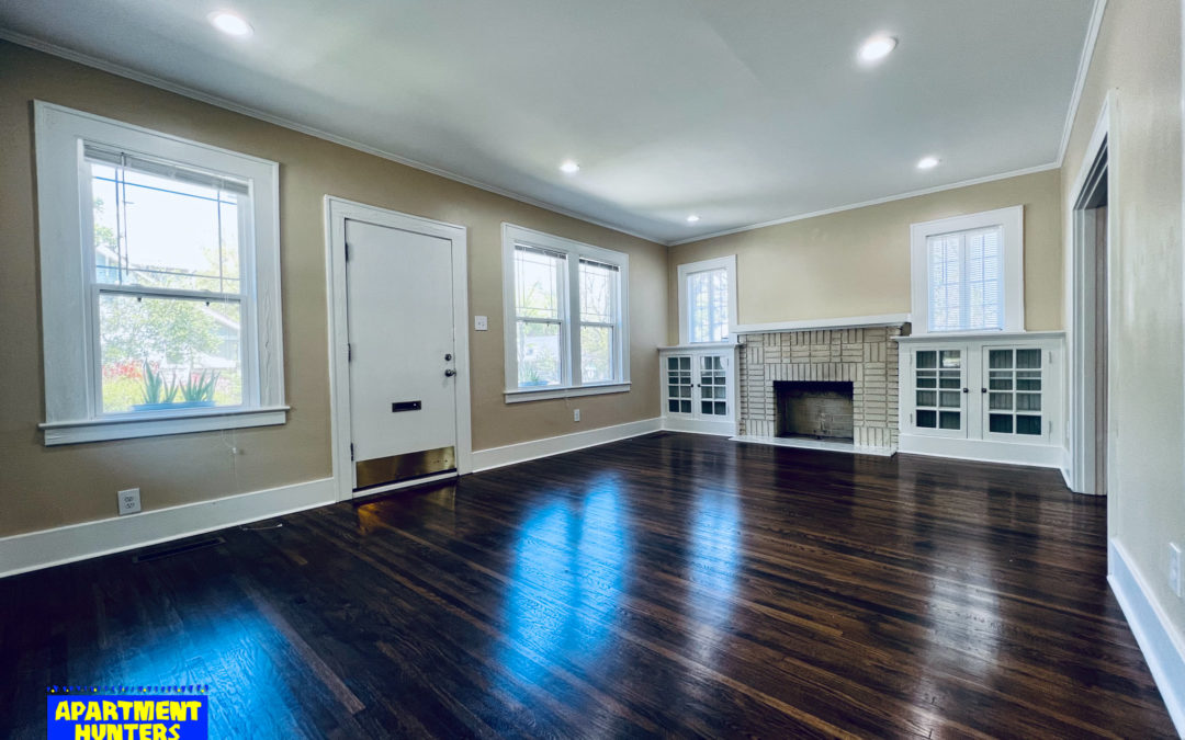 Spacious living room in a 3-bedroom Hillcrest home featuring hardwood floors, large windows, and a decorative fireplace, highlighting the charm of Little Rock's sought-after neighborhood near UAMS.