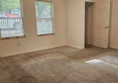 Spacious living area in a newly renovated duplex in Midtown Little Rock, featuring large windows, natural light, and plush carpeting.