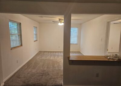 Newly renovated interior of a duplex in Midtown Little Rock, featuring a spacious living area with natural light, neutral walls, and carpeted flooring, showcasing the cozy atmosphere ideal for renters.