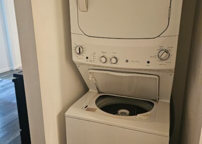 Stacked washer and dryer in a modern duplex laundry area, showcasing convenience and functionality in a newly renovated Midtown Little Rock home.