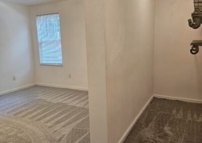 Newly renovated duplex interior showcasing a spacious room with natural light from a window, light-colored walls, and plush carpet, emphasizing modern updates in Midtown Little Rock.