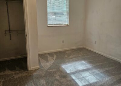 Newly renovated bedroom in Midtown Little Rock duplex, featuring fresh paint, new carpet, and a window providing natural light.