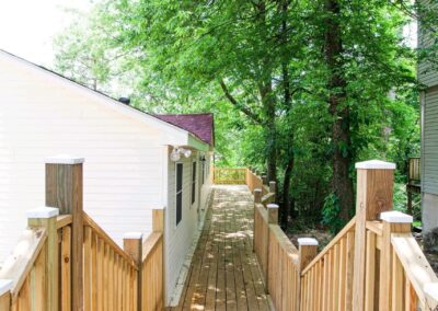 Newly renovated duplex in Midtown Little Rock featuring a wooden walkway leading to a bright home surrounded by lush greenery.