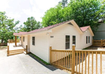 Newly renovated 3-bedroom, 2-bath duplex in Midtown Little Rock with modern exterior, wooden deck, and surrounded by greenery.