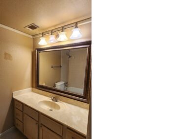 Updated bathroom vanity with light fixtures, large mirror, and beige walls in first-floor condo in Pleasant Woods, West Little Rock.