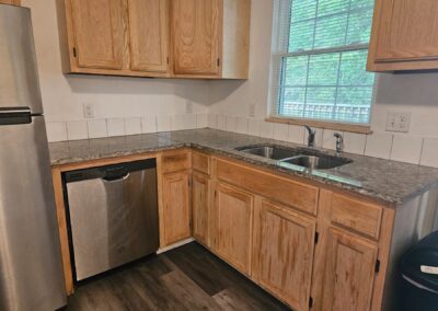 Updated kitchen with modern appliances, granite countertops, wooden cabinets, and double sink, showcasing the renovated duplex in Midtown Little Rock.