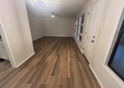 Interior view of a renovated Midtown home featuring modern wood flooring, natural light from large windows, and a ceiling fan, reflecting spacious living in a 4-bedroom, 2-bath rental property.