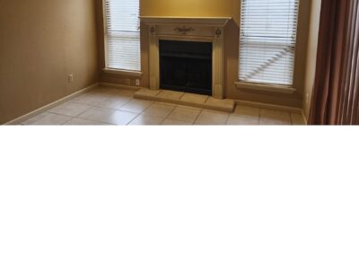 Elegant living room with a fireplace, tiled flooring, and natural light from two windows, showcasing the cozy atmosphere of the first-floor condo in Pleasant Woods, West Little Rock.