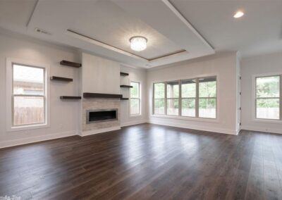 Spacious living room in a smart home in West Little Rock, featuring modern design elements, large windows for natural light, hardwood flooring, and a contemporary fireplace.