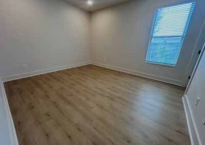 Spacious interior of a brand-new townhome in Argenta, featuring hardwood flooring, large window with blinds, and neutral walls, ideal for rental listings.