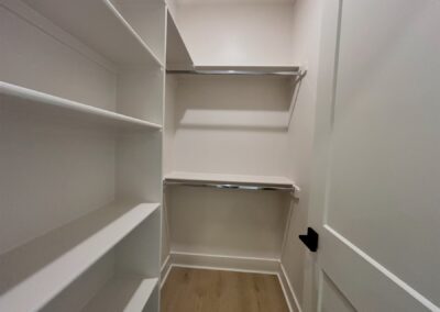 Spacious closet interior with white shelving and hanging rods, showcasing storage potential in a brand-new townhome in Argenta.
