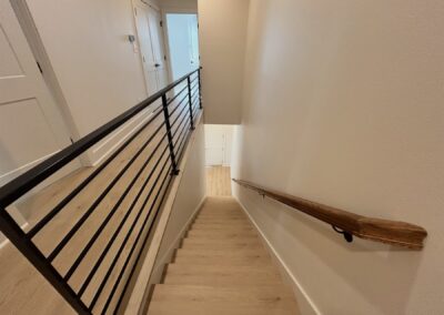 Modern staircase with wooden handrail and metal railing in a brand-new townhome located in the Argenta District, showcasing contemporary design and neutral colors.