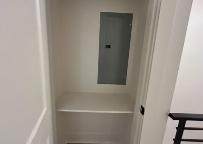 Utility closet with electrical panel and built-in shelf in a modern townhome in the Argenta District.