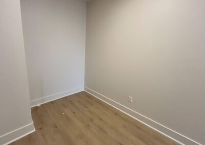 Empty room with hardwood flooring, neutral walls, and natural light, showcasing modern space in a brand-new townhome for rent in the Argenta District.