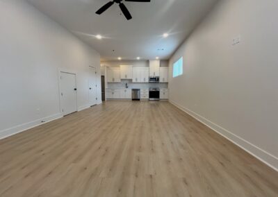 Modern townhome interior in Argenta District featuring hardwood flooring, open layout, kitchen with white cabinetry, and natural light from window.
