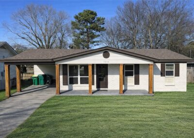 Fully renovated home in Midtown Little Rock featuring a modern exterior with new porch columns, landscaped yard, and driveway, showcasing the property available for rent at $1,399 per month.