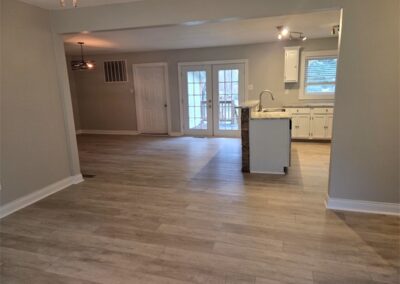 Fully renovated interior of a home in Midtown Little Rock, featuring new flooring, modern kitchen with white cabinetry, and access to a fenced yard through French doors.