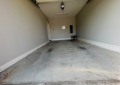 Spacious garage interior of a townhome in Benton, Arkansas, featuring concrete flooring and gray walls, suitable for parking and storage.