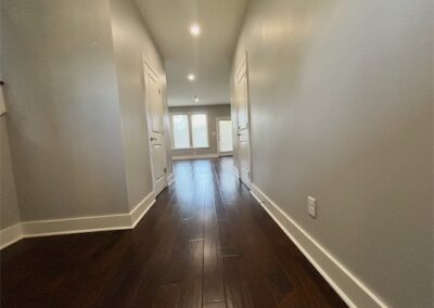 Spacious hallway in a modern Benton townhome featuring hardwood flooring, bright lighting, and doors leading to living areas.