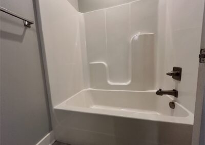 Modern bathroom with a clean white bathtub and shower combination, featuring sleek fixtures, part of a spacious townhome in Benton, Arkansas.