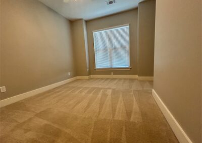 Spacious townhome interior in Benton, Arkansas, featuring carpeted floor, large window with blinds, and neutral wall colors, showcasing potential living space for rental property.