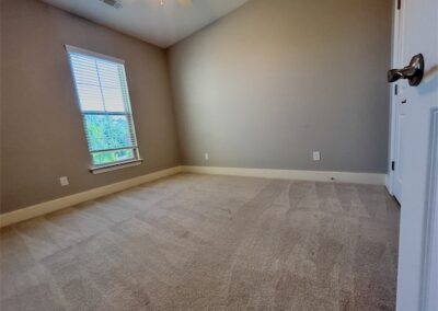 Spacious bedroom in a Benton, Arkansas townhome rental featuring natural light from a window, light-colored carpet, and neutral wall tones.