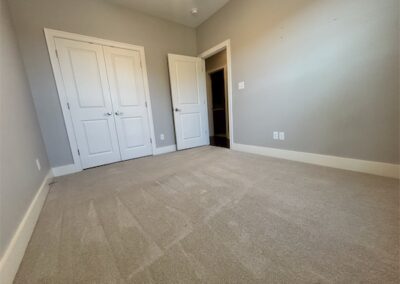 Spacious townhome interior in Benton, Arkansas, featuring beige carpet, double closet doors, and neutral gray walls, showcasing the available rental space.