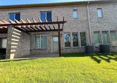 Spacious townhome backyard in Benton, featuring a patio with a pergola, well-maintained lawn, and modern brick exterior, highlighting outdoor living space.