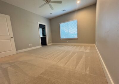 Spacious living room in a Benton, AR townhome featuring carpet flooring, ceiling fan, and natural light from a window, showcasing modern interior design.