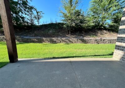 Private patio and small yard of a spacious townhome in Benton, Arkansas, featuring green grass and a stone wall backdrop.