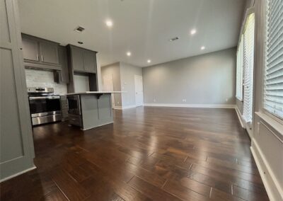 Spacious living area of a modern townhome in Benton, featuring hardwood flooring, an open layout, and a kitchen island with stainless steel appliances.
