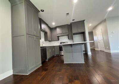 Modern kitchen interior featuring gray cabinetry, quartz countertops, stainless steel appliances, and hardwood flooring in a spacious townhome in Benton, Arkansas.