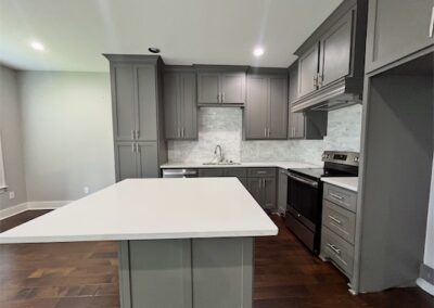 Modern kitchen in Benton townhome featuring quartz countertops, stainless steel appliances, and spacious island with hardwood flooring.