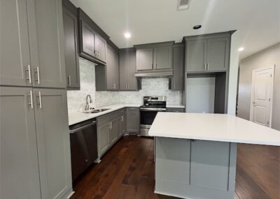 Modern kitchen in spacious Benton, AR townhome featuring gray cabinetry, quartz countertops, stainless steel appliances, and hardwood flooring.