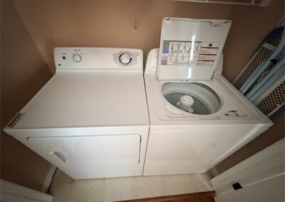 Washer and dryer set in a spacious laundry area of a West Little Rock home, featuring a top-loading washing machine and a front-loading dryer, emphasizing included appliances in rental listing.