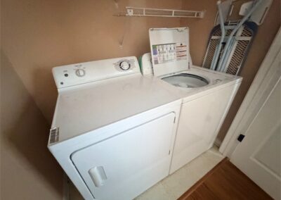Washer and dryer included in spacious West Little Rock home, featuring laundry area with ironing board and storage shelf.