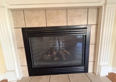 Fireplace with black frame and tile surround in spacious West Little Rock home, featuring elegant mantel and cozy design elements.
