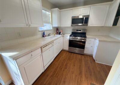 Modern kitchen in spacious West Little Rock home featuring stainless steel appliances, white cabinetry, and hardwood flooring.