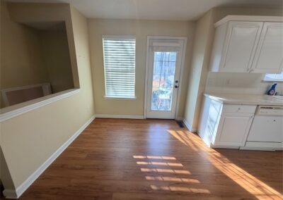Spacious kitchen area in West Little Rock home featuring hardwood floors, natural light from windows, and white cabinetry.