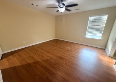 Spacious room with hardwood floors and ceiling fan, featuring natural light from window, ideal for rental in West Little Rock.