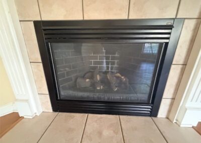 Fireplace with black frame and tiled surround in a spacious West Little Rock home, highlighting cozy interior features.