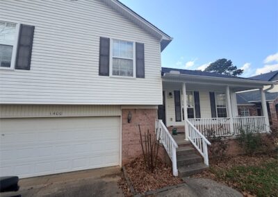 Two-story home in West Little Rock featuring a front porch, white siding, and a garage, highlighting spacious living and potential for renters.