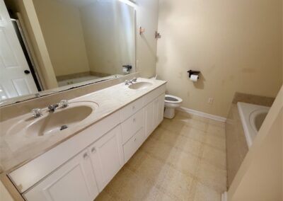 Spacious bathroom featuring dual sinks, large mirror, and a separate bathtub, designed for comfort and convenience in a West Little Rock home.