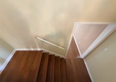 Staircase with hardwood steps leading to a doorway in a spacious West Little Rock home.