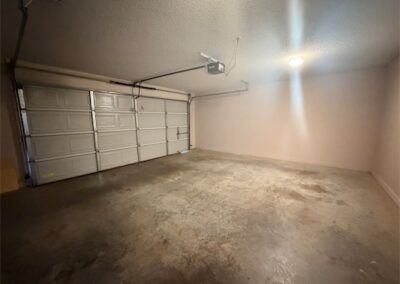 Spacious two-car garage with concrete floor and overhead lighting, featuring a large garage door, part of the West Little Rock home rental listing.